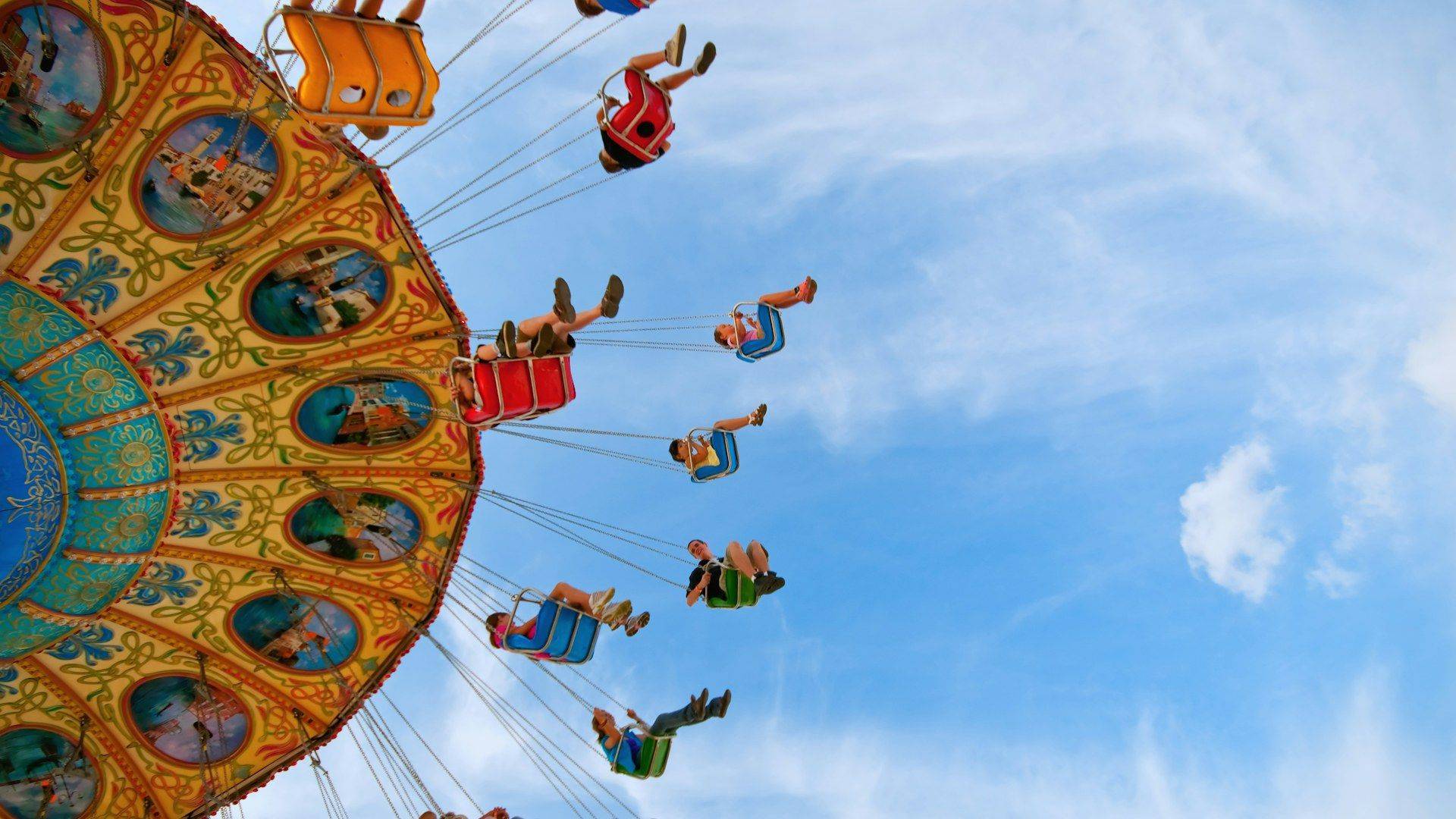Swing ride spinning against a blue sky at an amusement park, family vacation stress